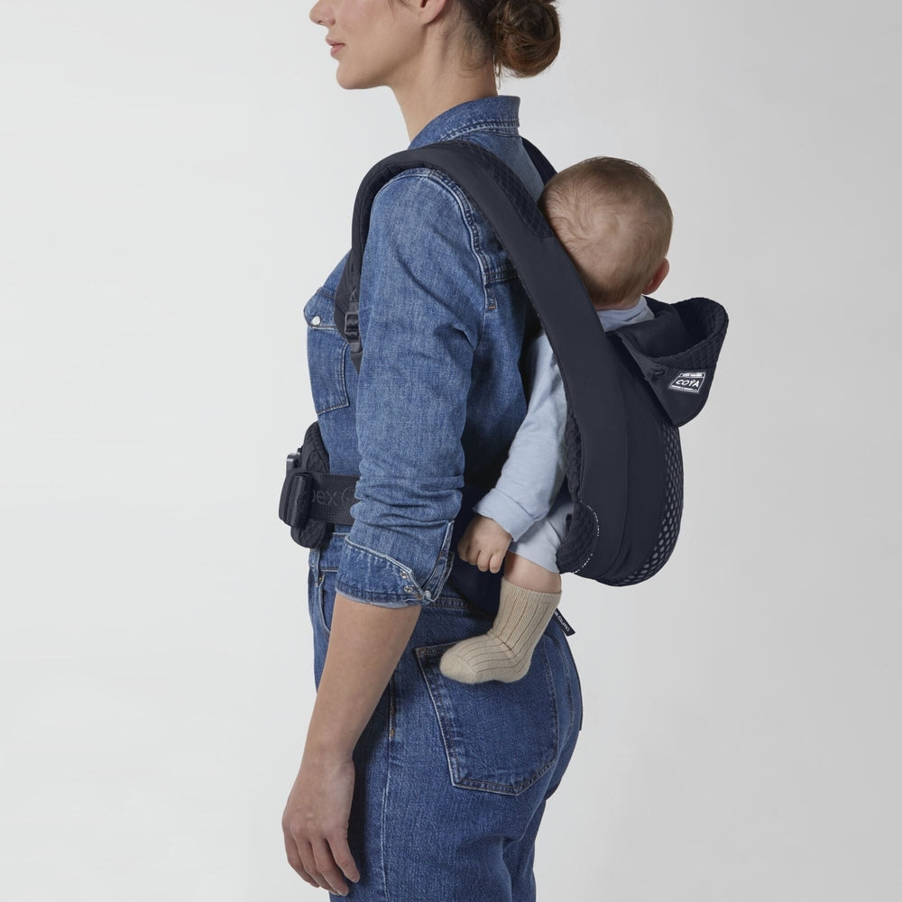 Dark navy Cybex Coya baby carrier on back; mesh panel and padded straps, baby in light blue outfit.