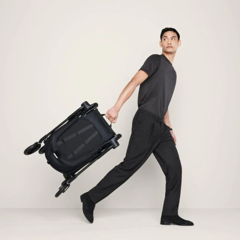 CYBEX Melio Carbon 3 ultralight stroller folded in black with visible wheels being carried