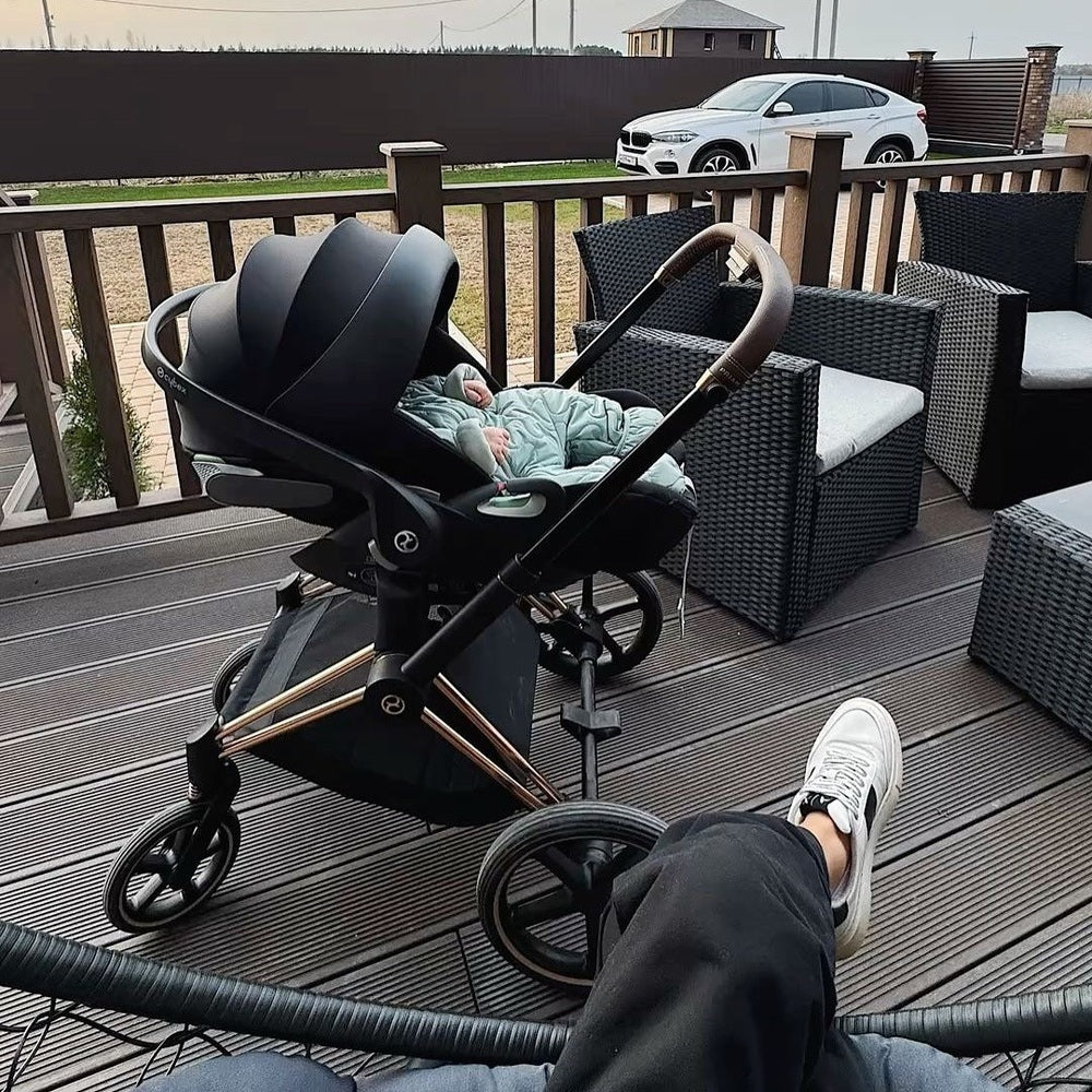 CYBEX Priam 4 stroller with Lux carry cot in sepia black and rose gold frame on a wooden deck