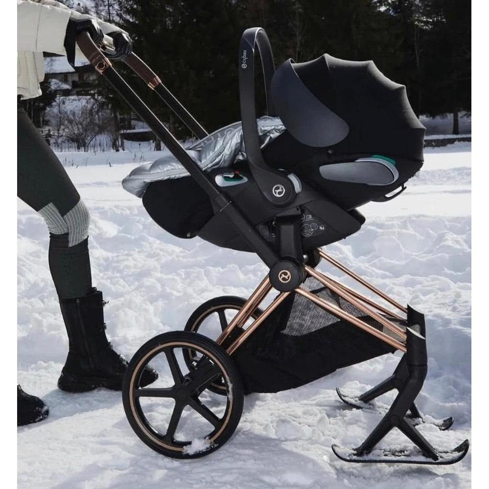 Cybex Priam 4 stroller with rose-gold frame and black sepia Lux carry cot in winter snow setting