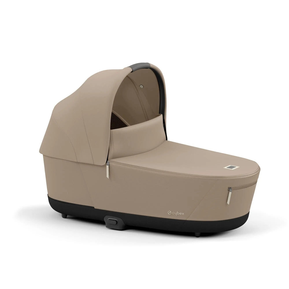 Cybex Priam Lux Carry Cot in beige with extended canopy, zipped side pockets, and a black base.