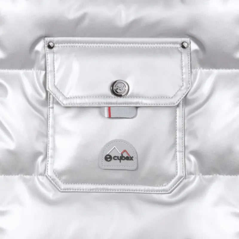 Cybex Winter Footmuff in silver, attached to stroller, showcasing a front pocket with snap and logo badge.