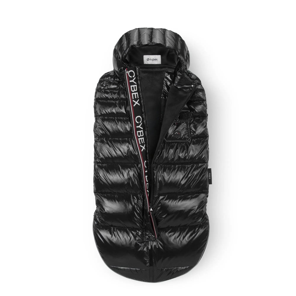 Cybex Winter Footmuff in black quilted fabric with hood, zip opening shows plush lining and CYBEX logo strap.