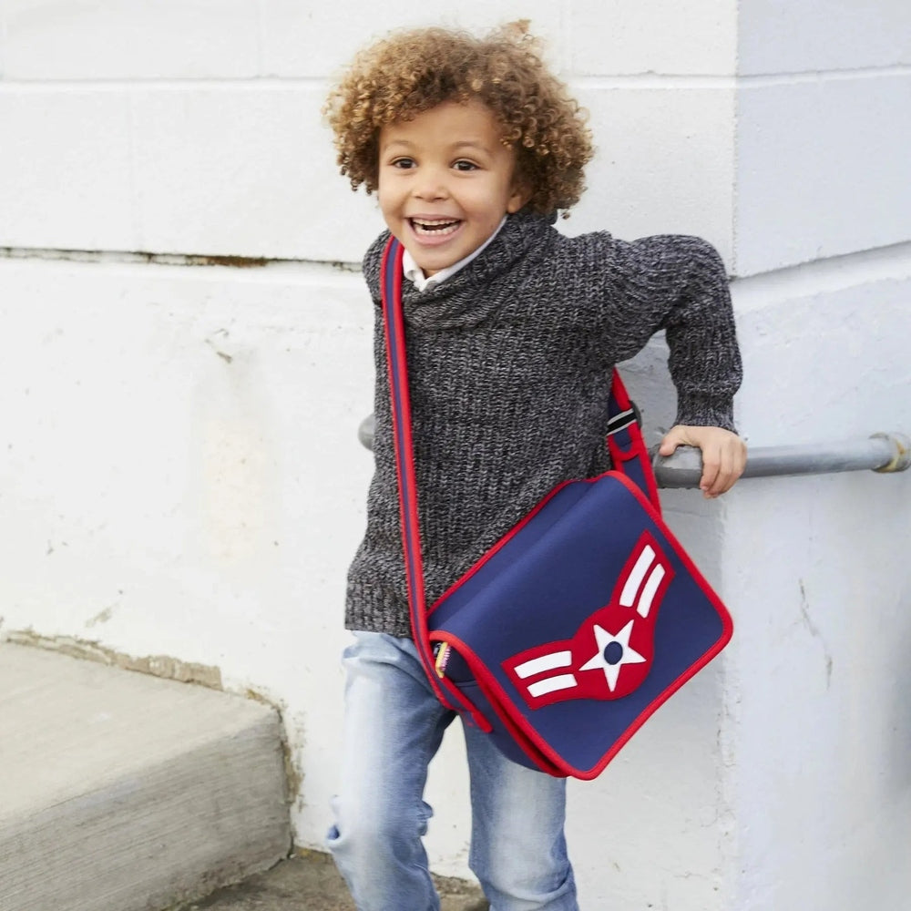 Dabbawalla Machine Washable Messenger Bag worn crossbody by a smiling child; blue bag with red trim and star emblem.