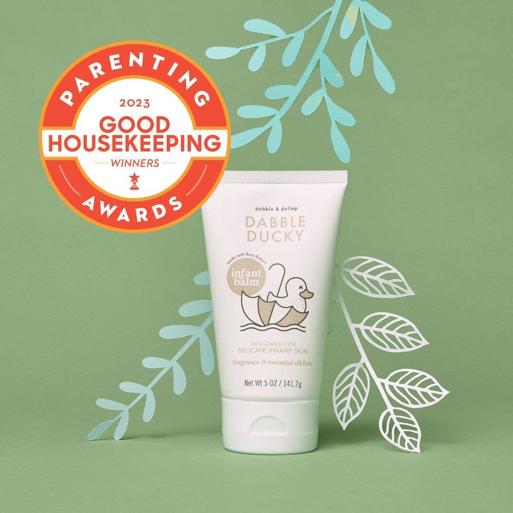 Dabble & Dollop All-Natural Infant Balm Fragrance-Free tube standing upright beside green leaves.