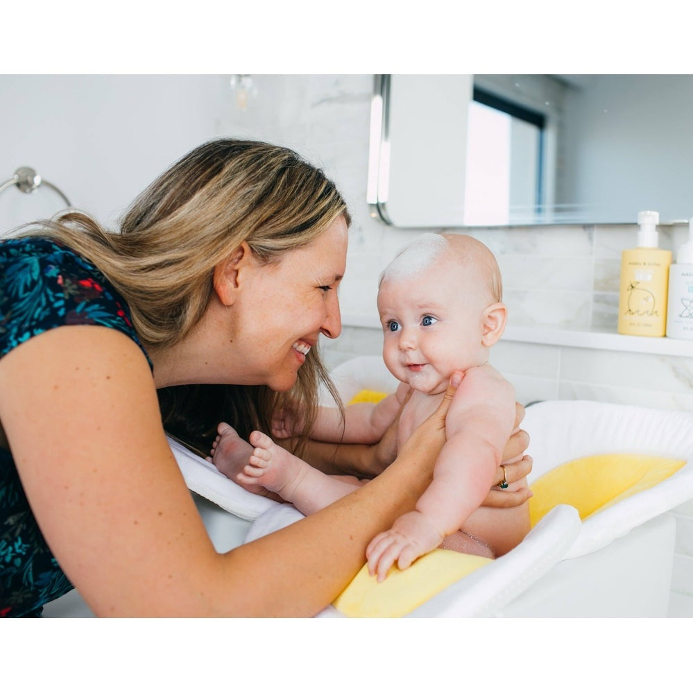Mom bathes a baby with Dabble & Dollop All-Natural Shampoo, Body Wash & Bubbles Lemon, creating a foamy head.