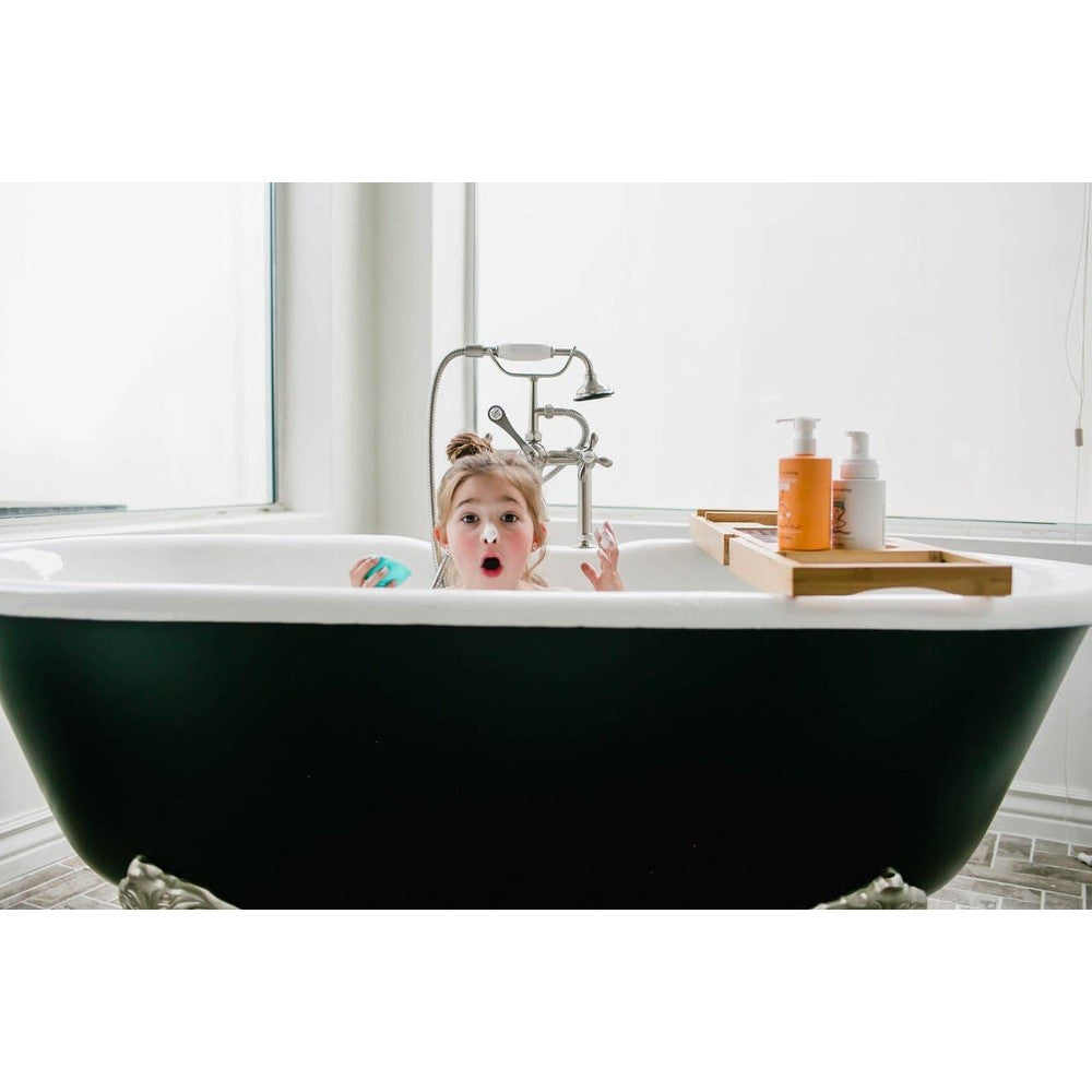 Child in a bathtub plays with bubbles as Dabble & Dollop All-Natural Shampoo, Body Wash & Bubbles Tangerine rests on a wooden bath tray.