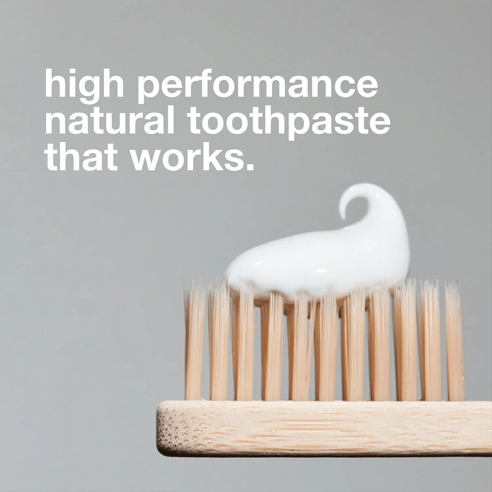 DAVIDS Toothpaste Fluoride Free Herbal Citrus Peppermint sits as white foam on bamboo toothbrush bristles.