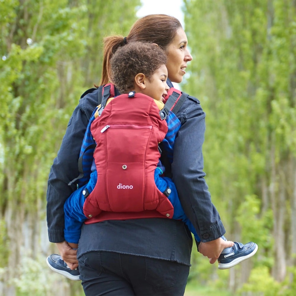 Diono Carus Essentials 3-in-1 Baby Carrier in red, worn on mom's back as she hikes with her child.