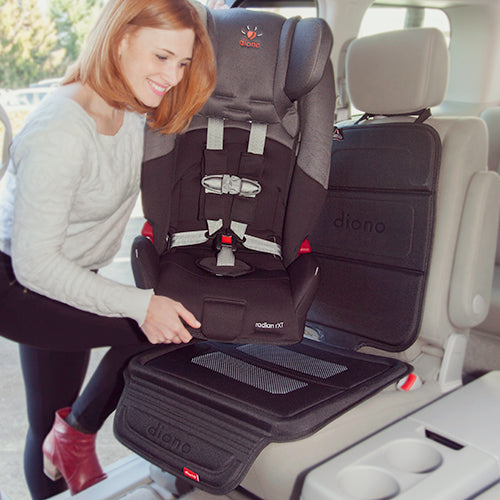 Diono Seat Guard Complete car seat protector in black, installed in SUV as a woman secures a child car seat.