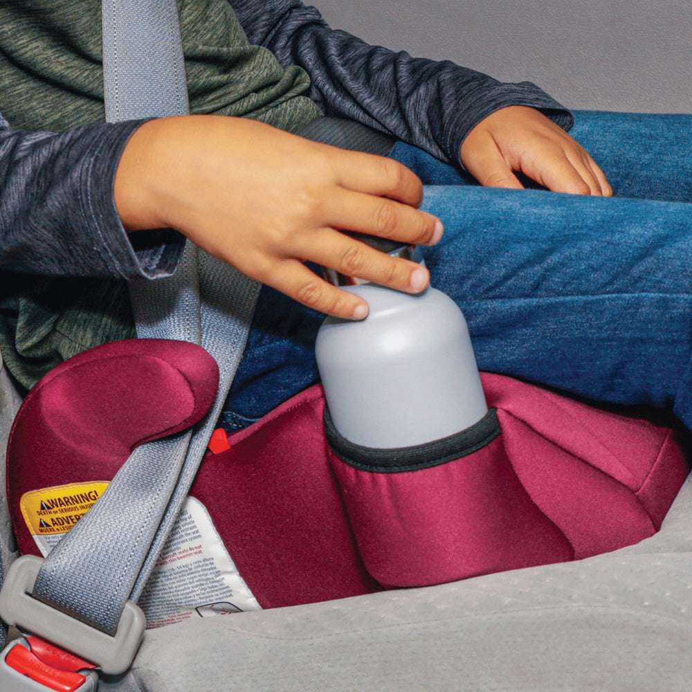 Diono Solana backless booster car seat in magenta with gray cup holder, child placing a bottle.