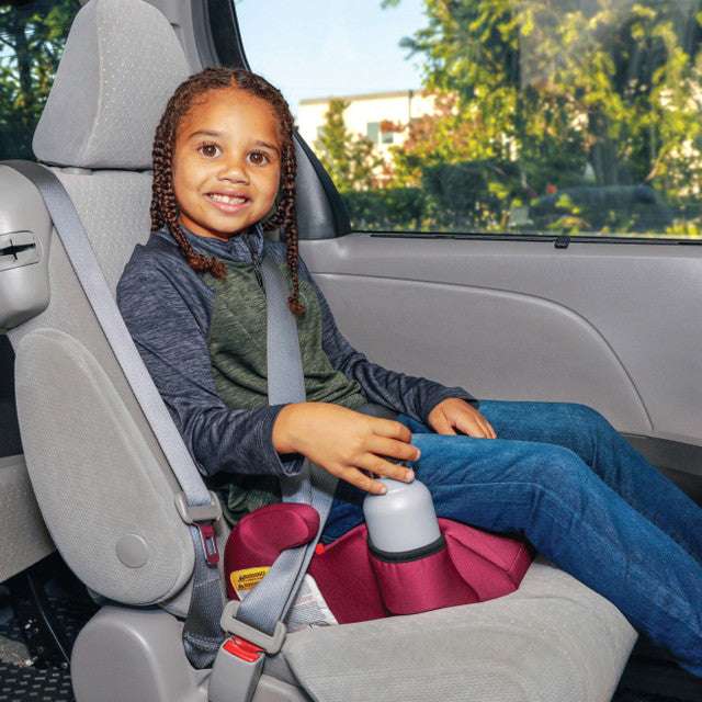 Diono Solana pink backless booster seat in car with smiling child buckled in.