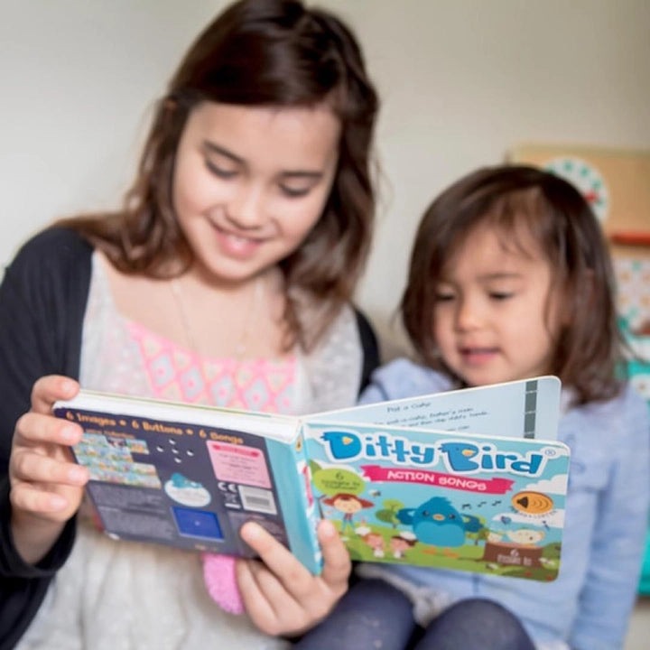 Ditty Bird Sound Book Action Songs USB-C Rechargeable, two smiling kids share the colorful educational toy.