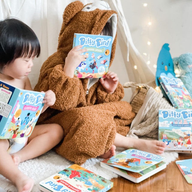 Ditty Bird Sound Book Animal Songs USB-C Rechargeable; kids in a fuzzy onesie read and listen to colorful Ditty Bird stories.