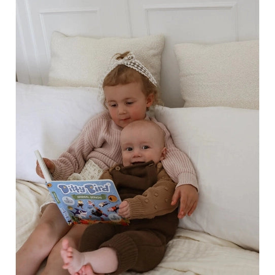 Ditty Bird Sound Book Animal Songs USB-C Rechargeable read by two babies cuddling on a white bed.