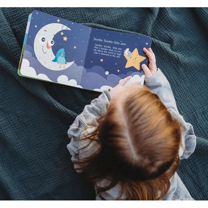 Ditty Bird Sound Book Bedtime Songs by DITTY BIRD, being read by a child on a deep blue blanket.