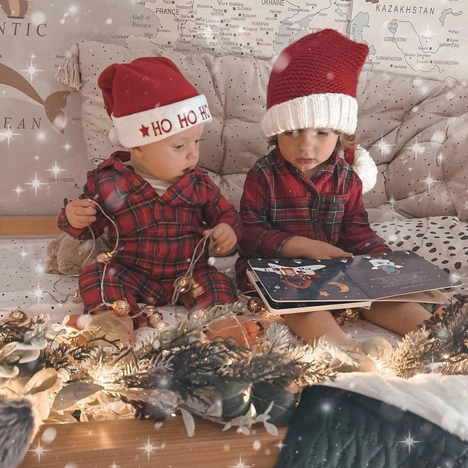 Ditty Bird Sound Book Christmas Songs USB-C Rechargeable, two toddlers in red plaid pajamas sit reading beside festive lights.
