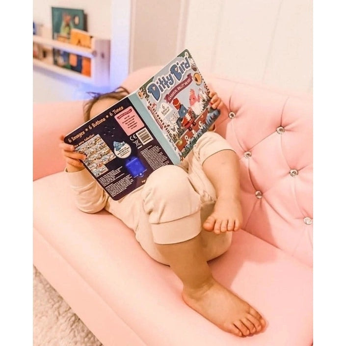 Ditty Bird Sound Book Classical Ballet Music USB-C Rechargeable; child sits on a pink couch reading the book, showcasing the educational toy.
