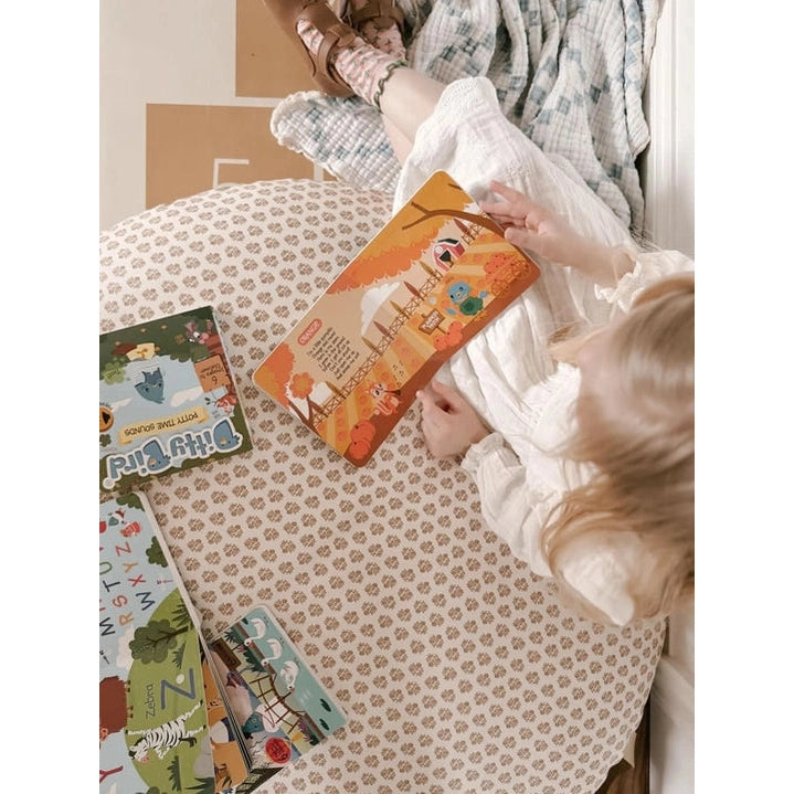 Ditty Bird Sound Book Color Songs USB-C Rechargeable held by a child on a cozy bed with colorful pages visible