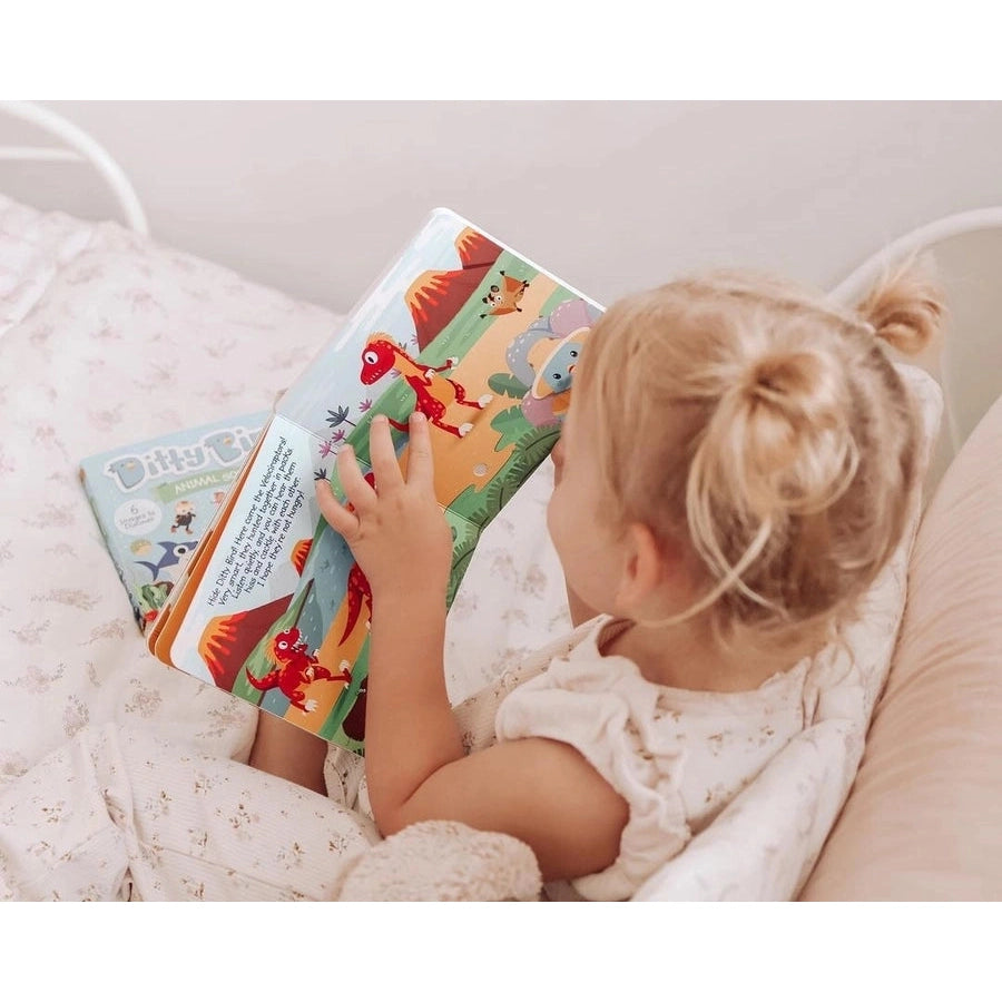 Ditty Bird Sound Book Dinosaur Sounds USB-C Rechargeable toddler reading and turning pages in bed.