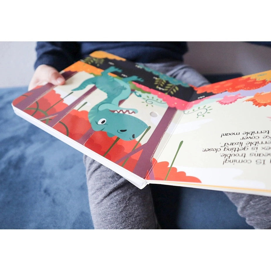 Ditty Bird Dinosaur Sounds USB-C Rechargeable sound book held open by a child, showcasing bright dinosaur illustrations.