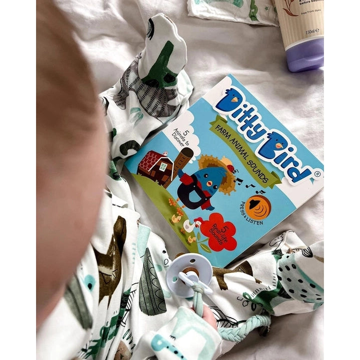 Ditty Bird Sound Book Farm Animal USB-C Rechargeable, blue cover; baby sits in printed pajamas beside the book.