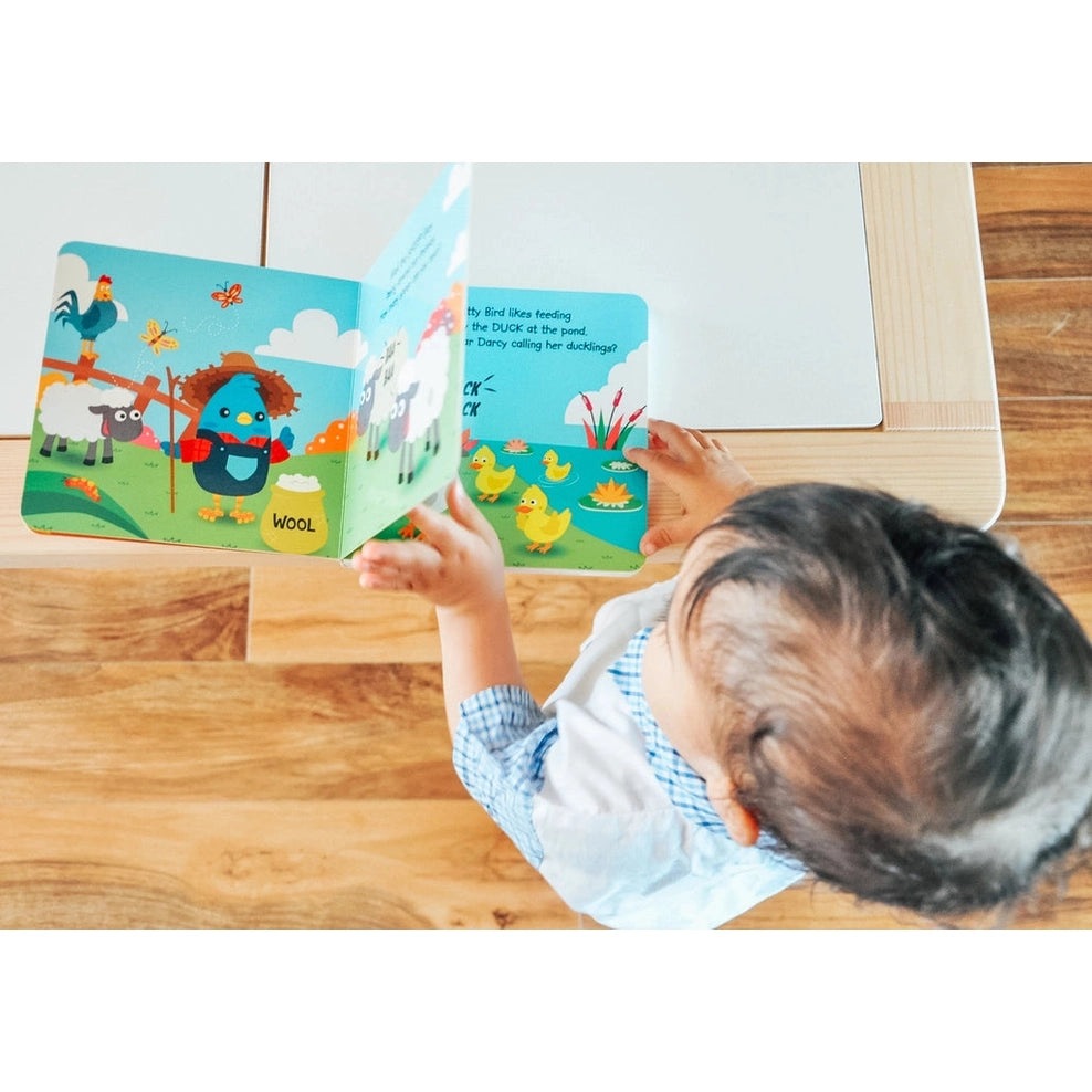 Ditty Bird Sound Book Farm Animal USB-C Rechargeable being read by a child on a wooden table with colorful farm scenes.