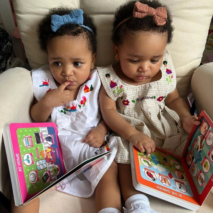 Ditty Bird Sound Book First 100 Words USB-C rechargeable, two babies in bows reading colorful educational books on a couch.
