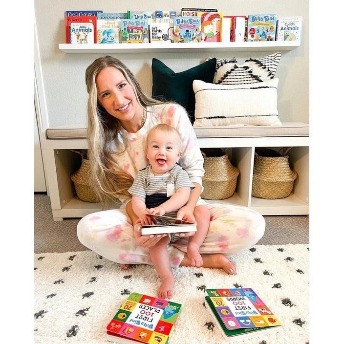 Ditty Bird Sound Book First 100 Words USB-C Rechargeable; baby taps the book while mom smiles nearby on a cozy rug.