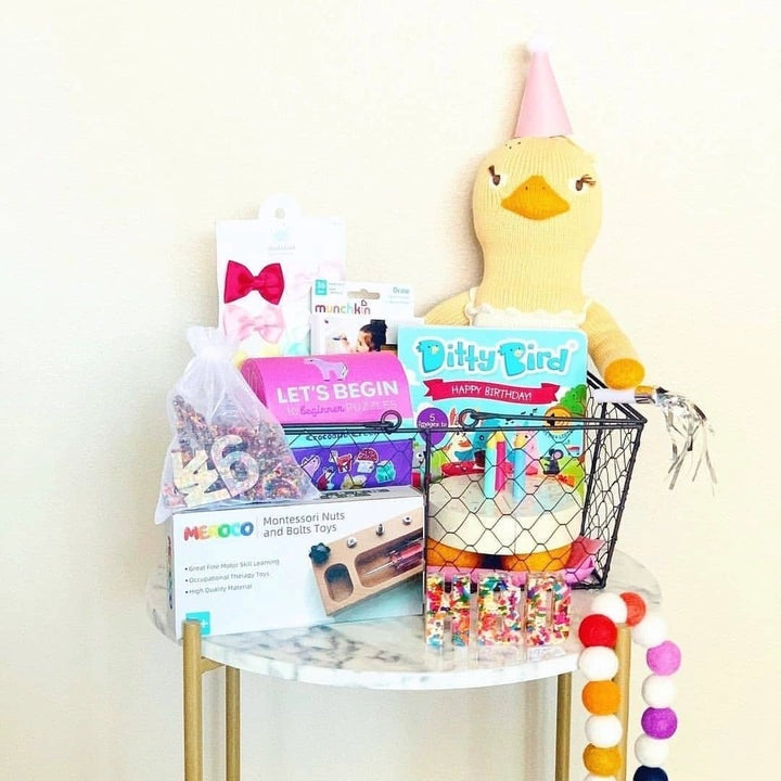 Ditty Bird Sound Book Happy Birthday USB-C Rechargeable in a gift basket with plush duck and colorful toys.