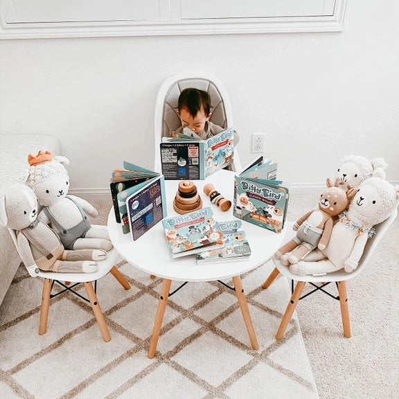 Ditty Bird Sound Book Happy Birthday USB-C Rechargeable set; child sits at a round table, reading and listening to storybooks.