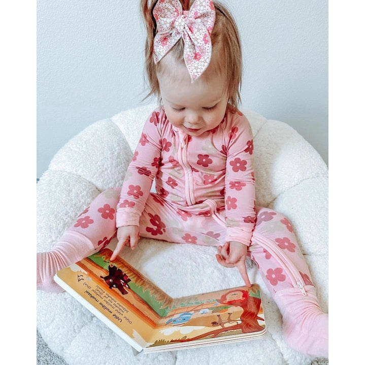 Ditty Bird Sound Book Safari Animal Sounds USB-C Rechargeable baby in pink floral onesie points at illustrated pages.
