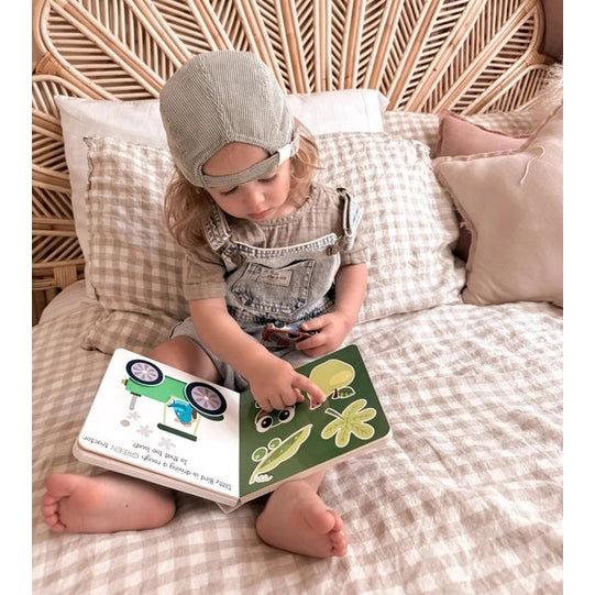 Ditty Bird Sound Book Touch the Colors USB-C Rechargeable; toddler sits on a bed, tapping colorful pages.