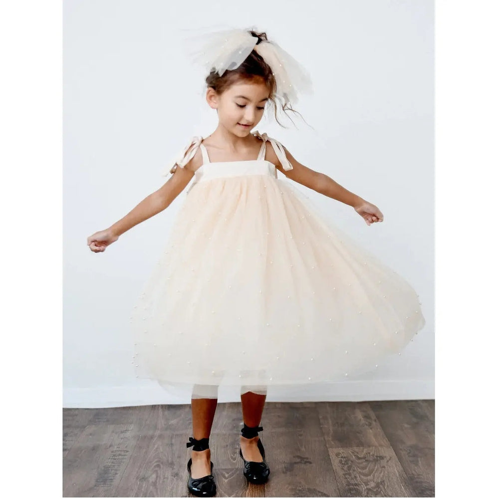 Dolly By Le Petit Pearl 2-Cute Tulle Dress Cream: girl twirls in cream party dress with bow-strap shoulders.
