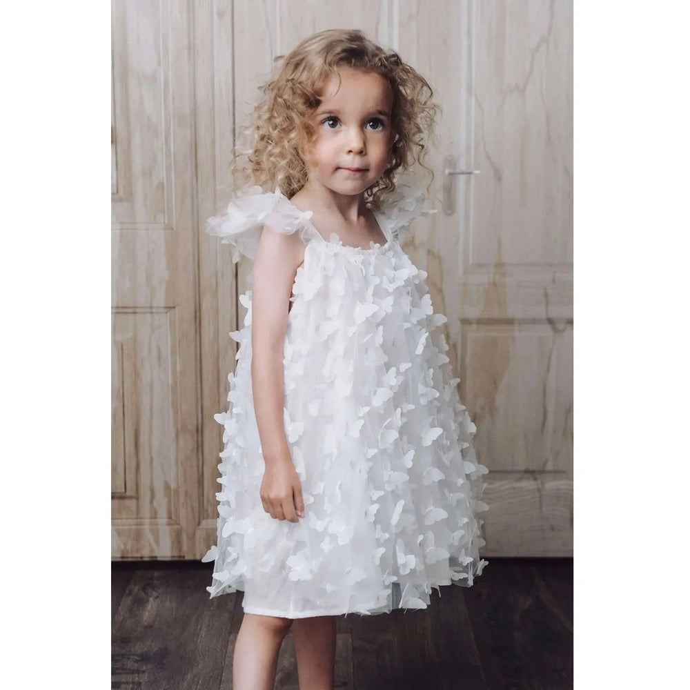 Dolly by Le Petit Tom Allover Butterflies Tutu Dress White: toddler stands in a white butterfly-applique tulle dress.