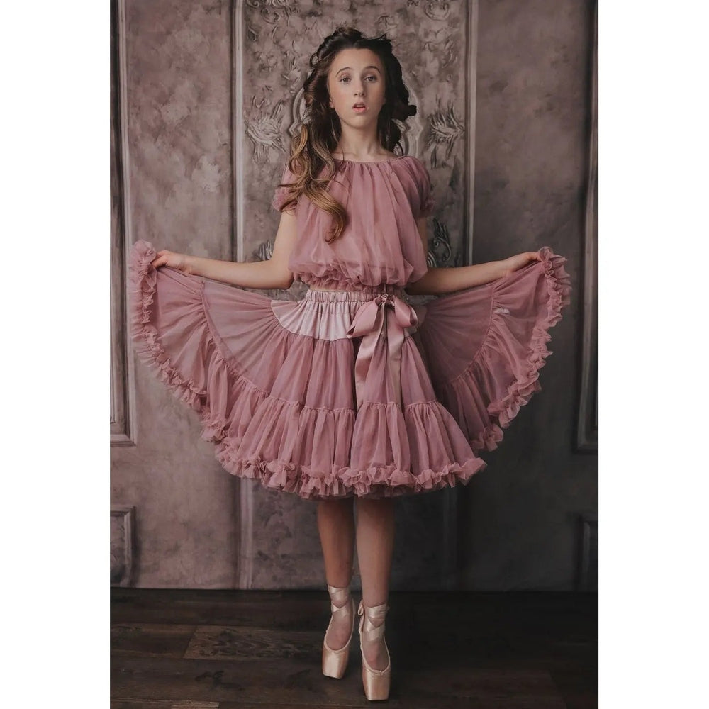 Dolly By Le Petit Tom Frilly Princess Top Mauve dress; girl lifts the tiered ruffled skirt to show the waist bow.