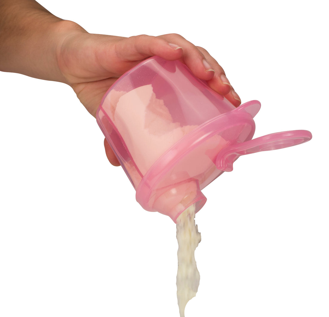 A hand is holding Dr. Brown's Baby Formula Dispenser, a pink container with compartments, pouring white powder through its spout. The dispenser from Dr. Brown's has an attached lid, set against a plain white background
