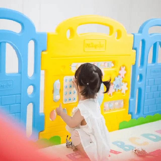 Dwinguler Castle Play Room Set in blue and yellow; a toddler kneels and toys with interactive panels.