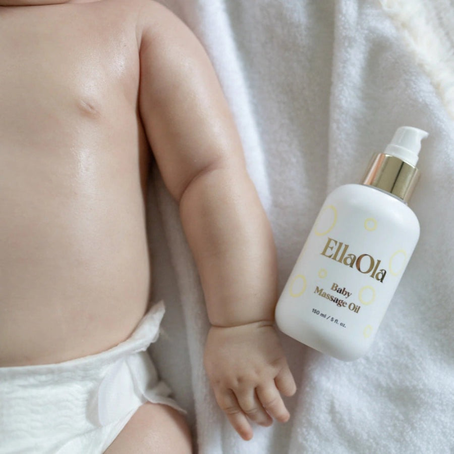 EllaOla Fragrance Free 100% USDA Organic Baby Massage Oil 150ml beside a naked baby on a white towel, ready for massage.