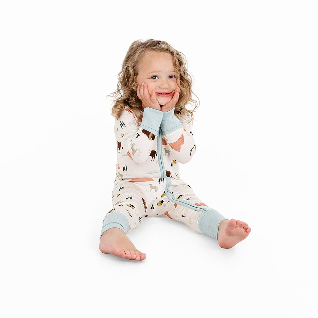 Seated child in On The Ranch bamboo convertible baby pajama showing mint cuffs and two-way zipper