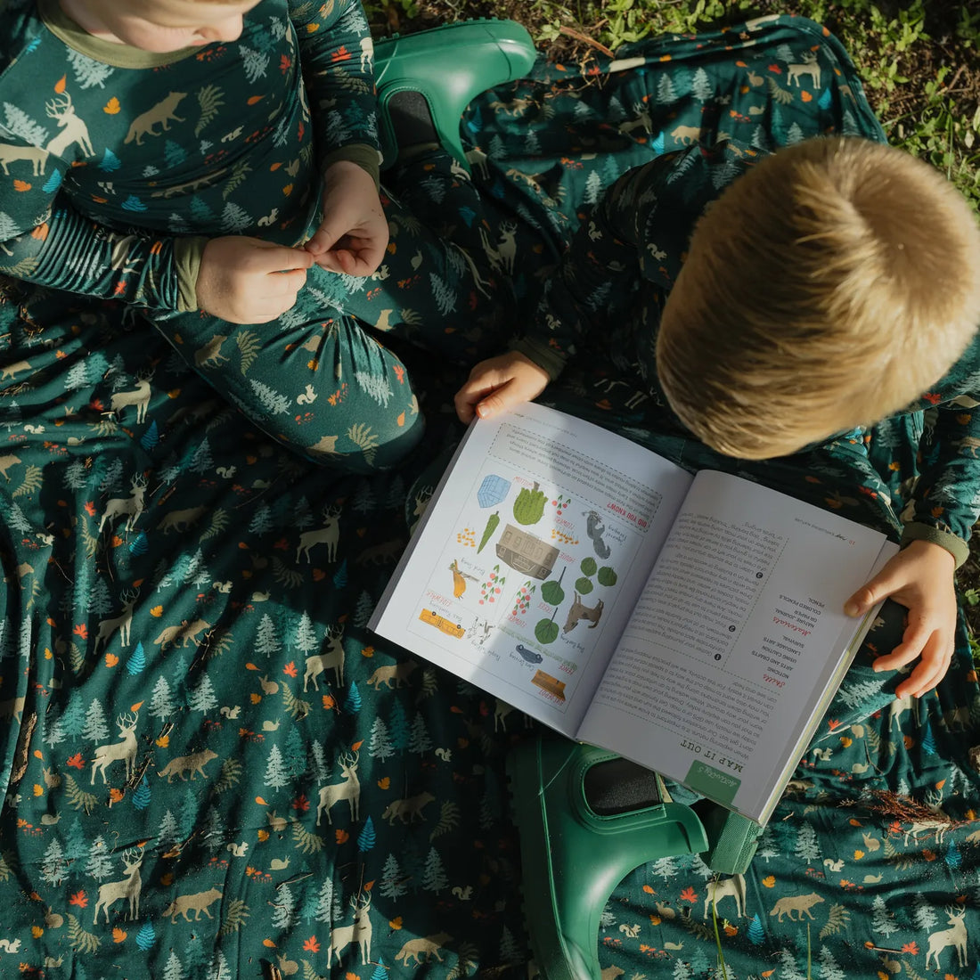 Two children wearing Midnight Forest pajamas with matching bamboo blanket outdoors