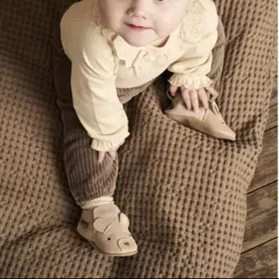 EN FANT Rose Dust suede baby slippers on a brown knitted surface