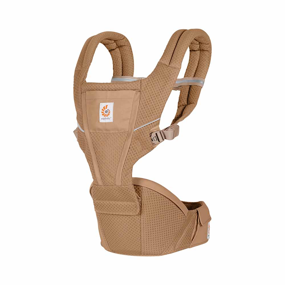 Ergobaby Alta Hip Seat Baby Carrier in tan worn by a caregiver, showing padded shoulder straps and wide waist belt.