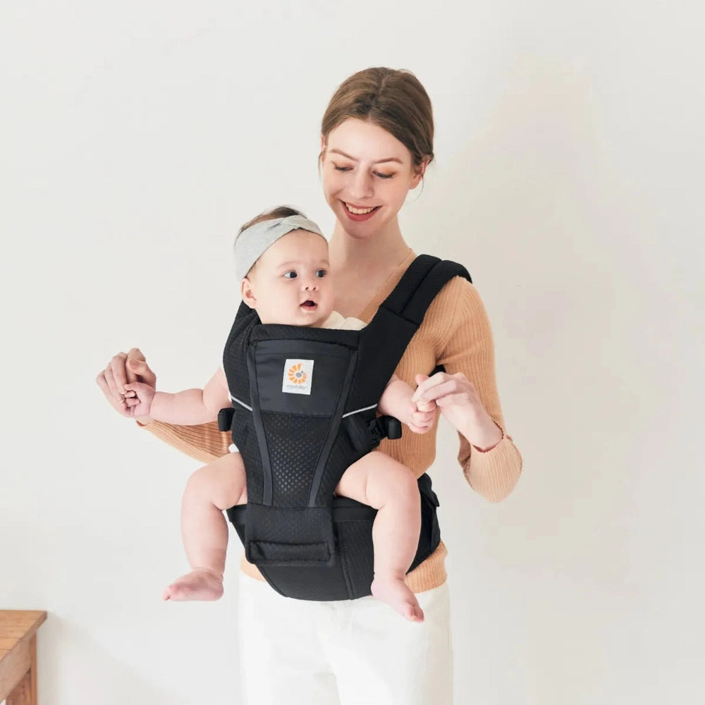 Ergobaby Alta Hip Seat Baby Carrier in black with a baby secured on the front hip.