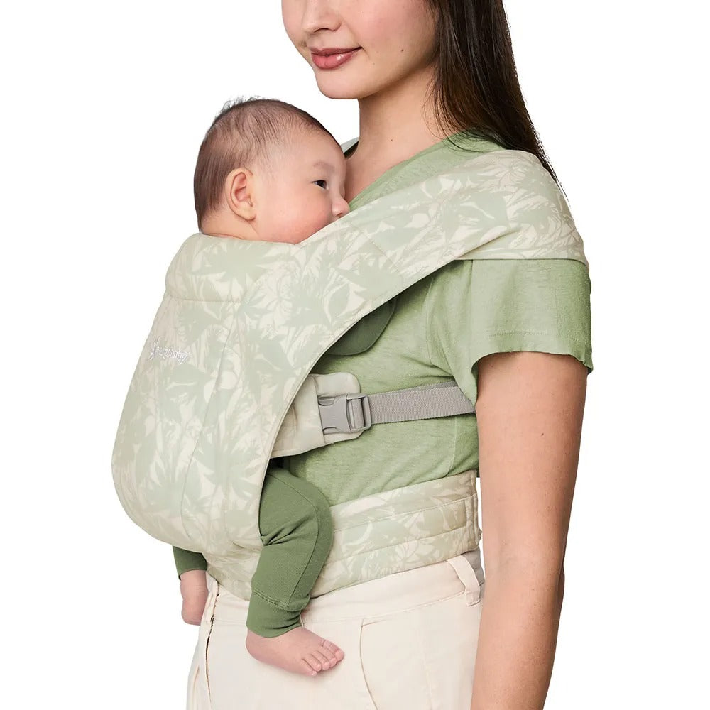 ERGOBABY Ergobaby Embrace Knit Newborn Carrier Sage Meadows in sage green, a mom securely holding her newborn close.