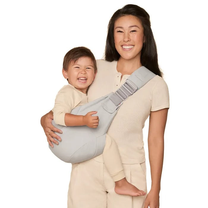 ERGOBABY Upsie Sling Carrier in light gray, front-carry with baby snug in sling, mom smiling.