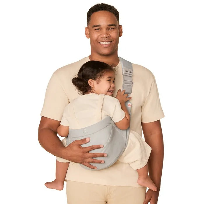 Ergobaby Upsie Sling Carrier in light gray worn by dad as a smiling toddler sits securely on his back.