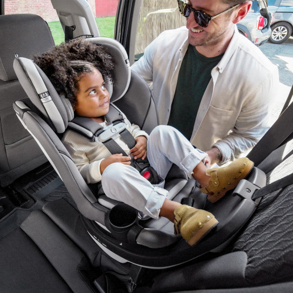 Evenflo Gold Revolve360 Slim 2-in-1 Rotational Car Seat with SensorSafe, gray; child secured in car.