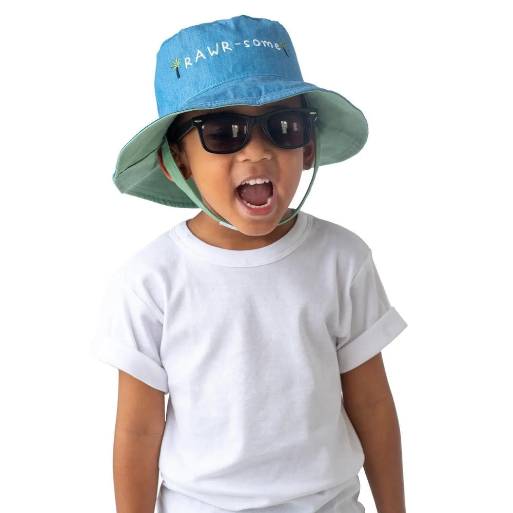 Flapjackkids Reversible Kids Sun Hat Dinosaur & Surfer Dino, blue top with green brim; child wears it for sun protection.