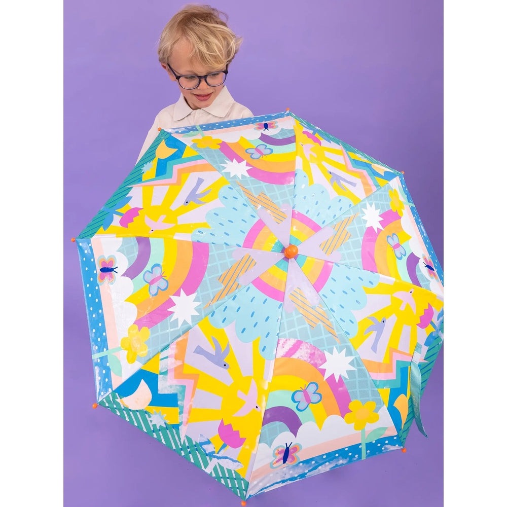Floss And Rock Color Change Umbrellas Rainbows; child holds a bright rainbow umbrella with colorful panels.